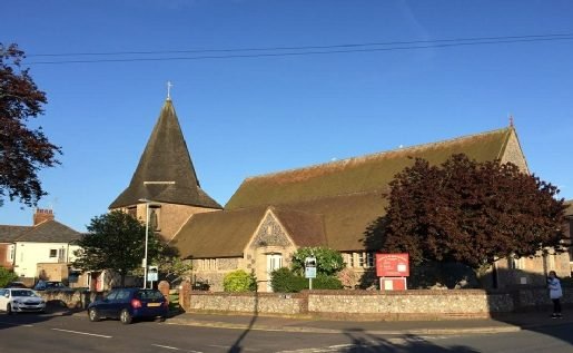 St John&rsquo;s in evening light, seen along Elm Grove with the flint boundary wall in front.