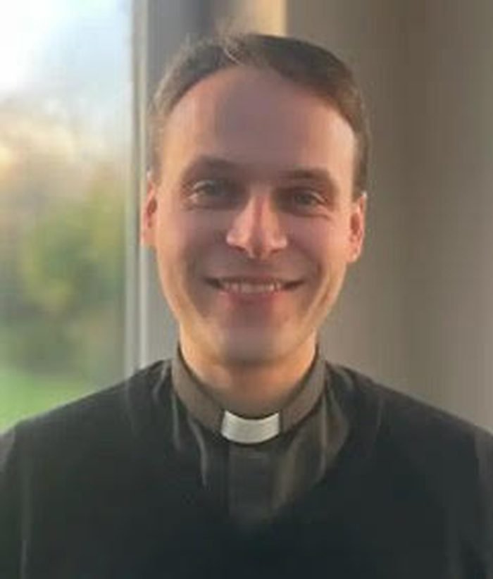 Fr Thomas Cotterill SSC, in a black cassock, smiling.
