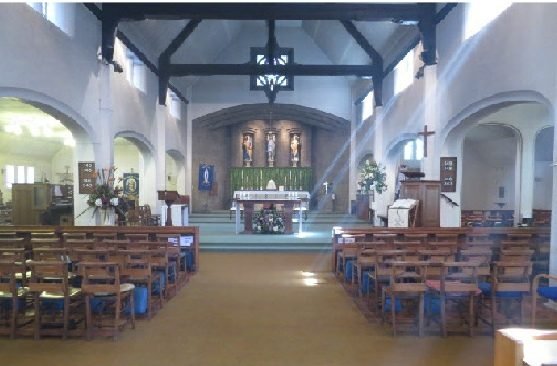 The nave of St John&rsquo;s looking east towards the high altar, with light falling across the chairs.
