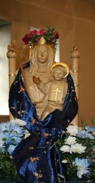 The statue of Our Lady of Walsingham in the church, robed in blue and gold and surrounded by flowers.